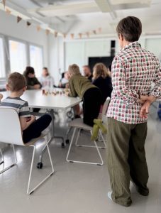 Tarinoilla toimijuutta -työpaja. Lapset tarinoivat pöydän ääressä, Minna ohjaa sivusta.